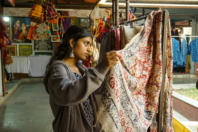 Woman examining fabric and other art works, handicrafts at an dilli haat artists fair