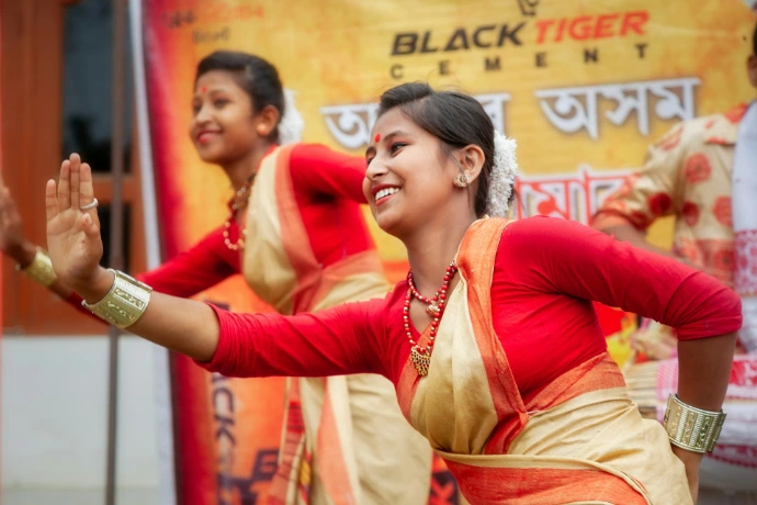 Two women in traditional attire performing a dance showing artists from Assam.